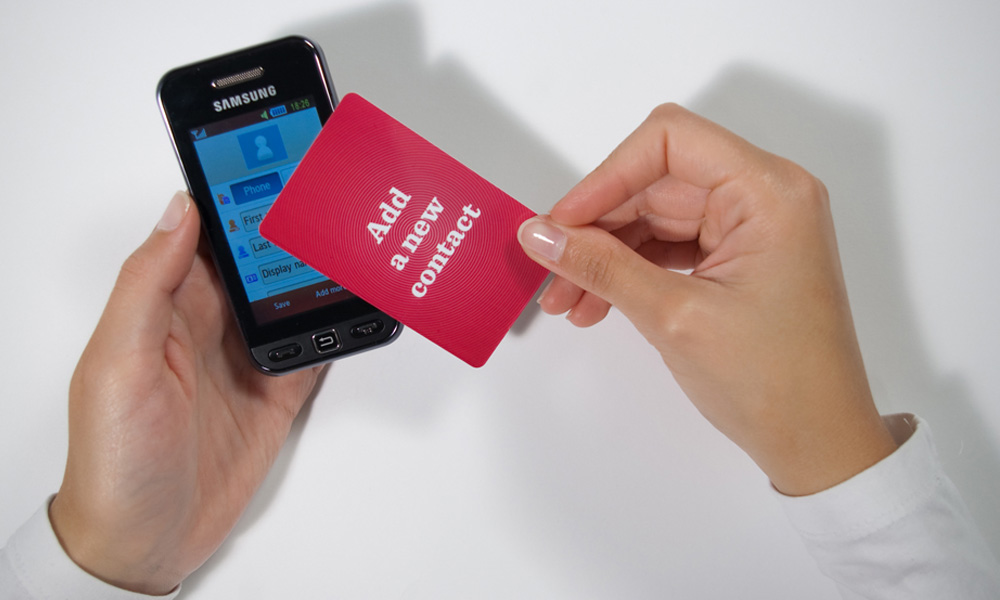 Top view of a person placing a 'add new contact' card on top of a phone